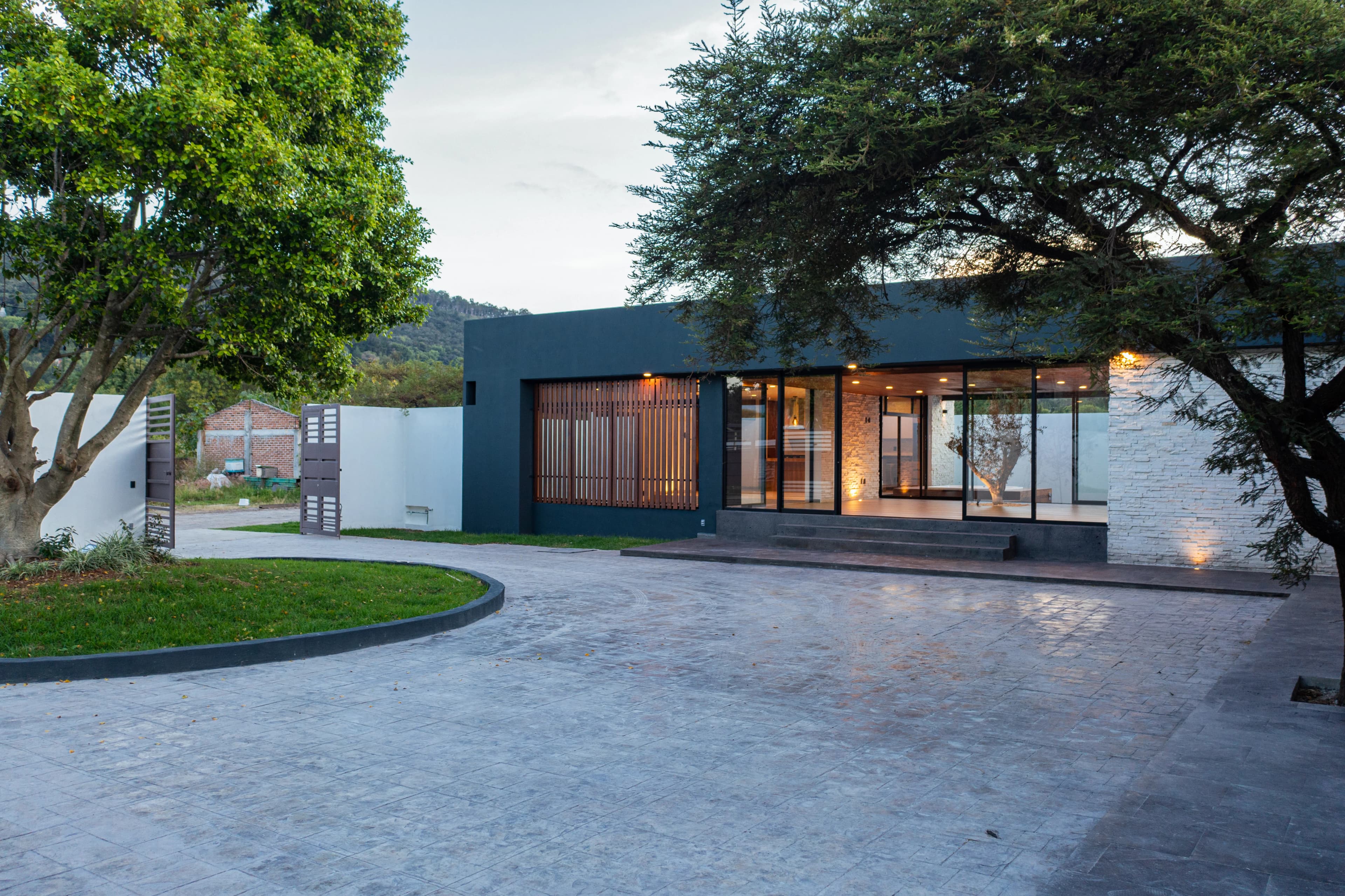 Fachada de Casa Cointzio al atardecer, alargada en un nivel sobre explanada de piedra
