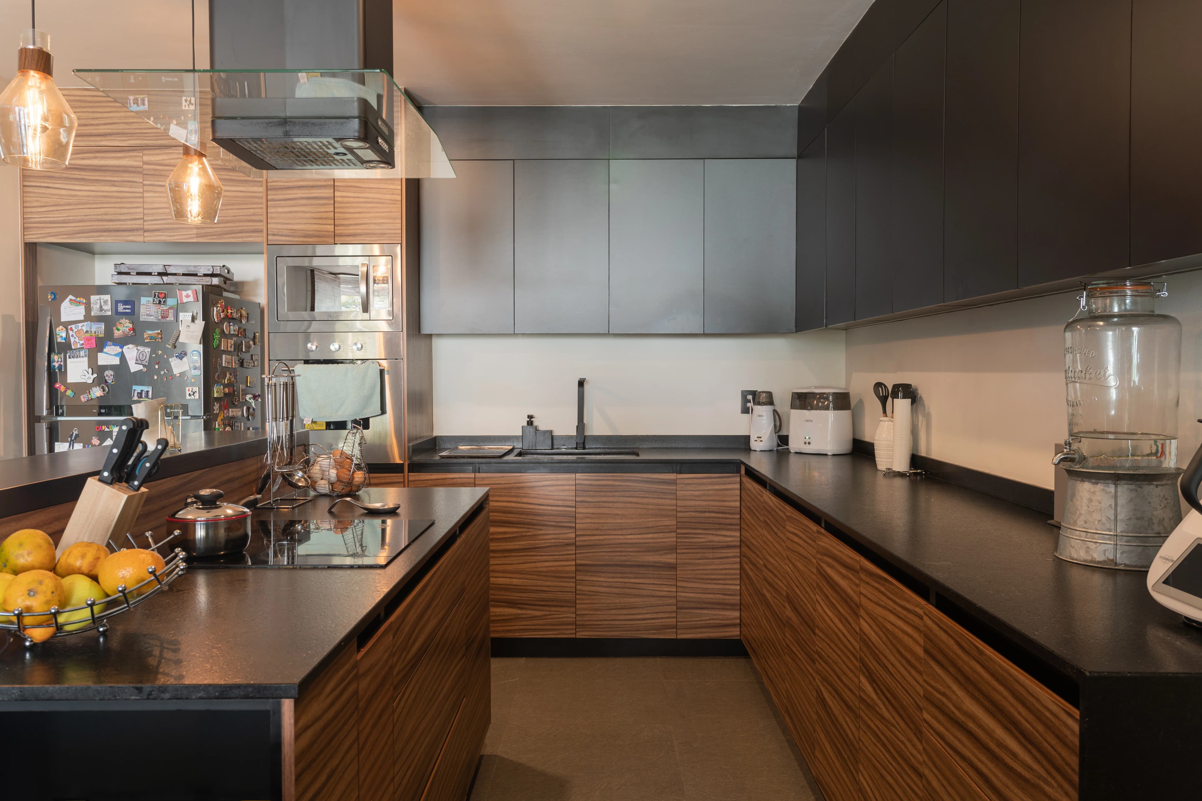 Cocina de Casa Zorros con isla en U, frentes de madera y alacena gris