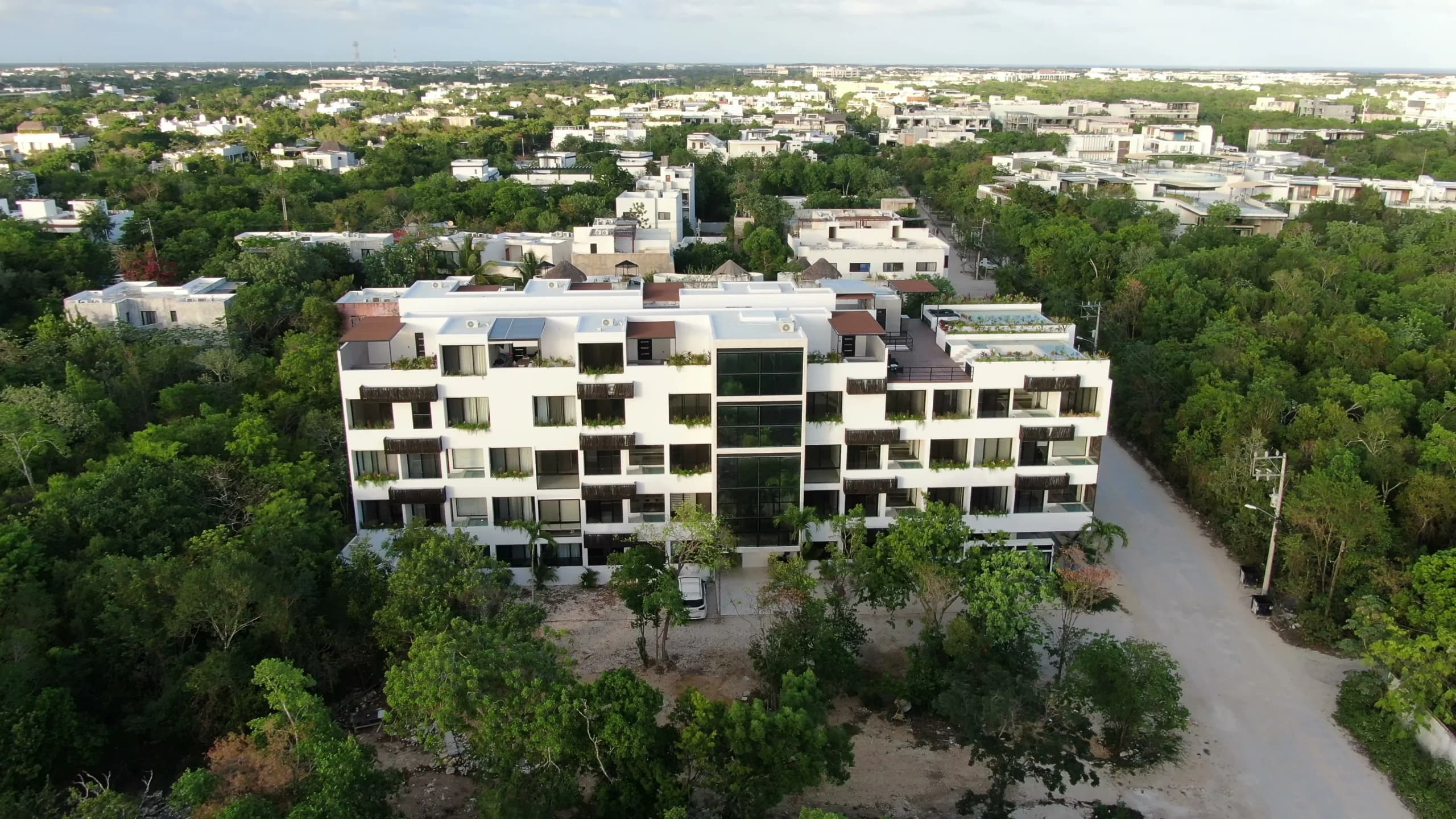 Fachada de Hygge al atardecer, con jardineras en cada balcón sobre la selva de Tulum