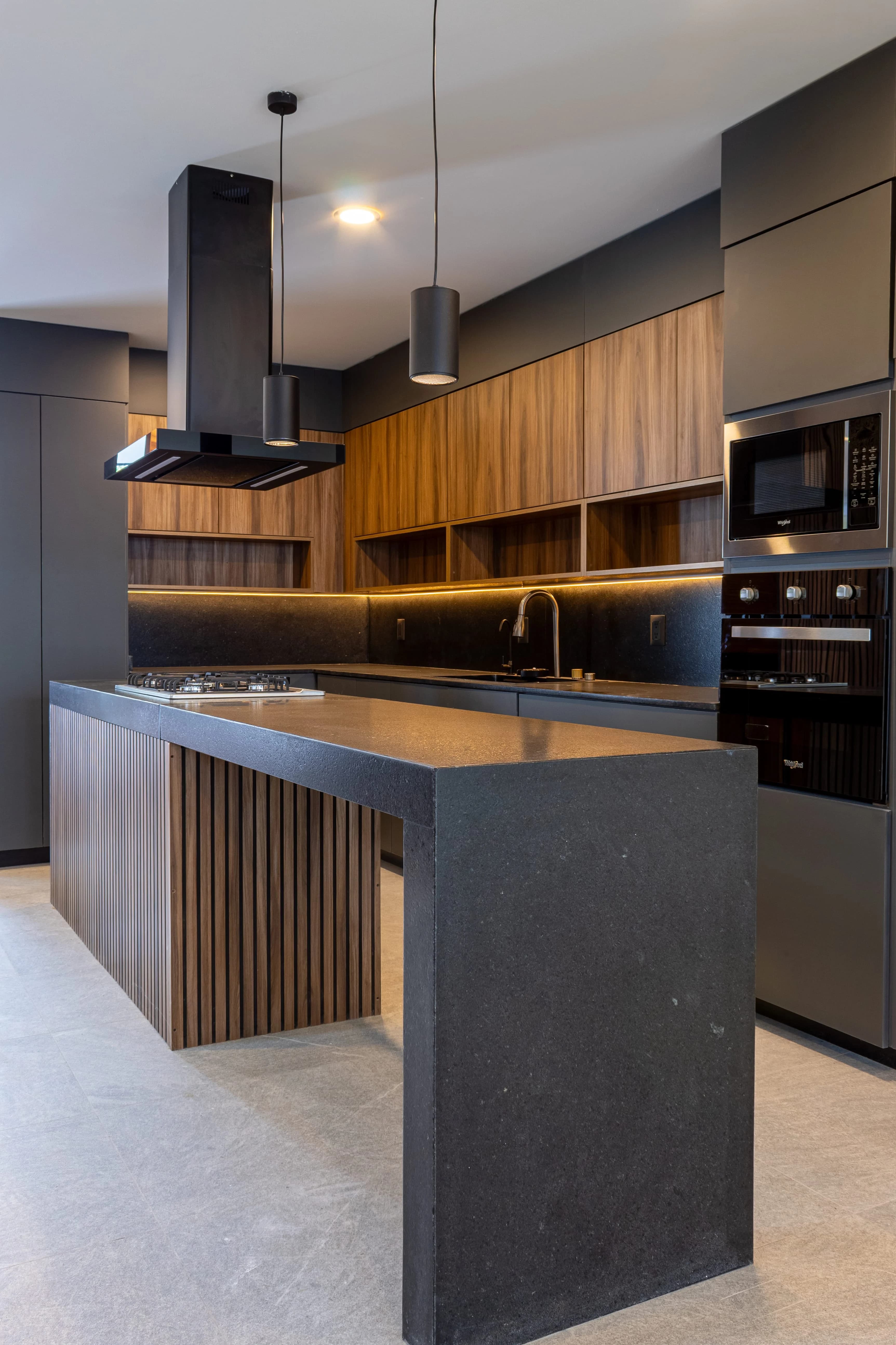 Cocina de Casa Encinos con isla de concreto, campanas negras y frentes de madera