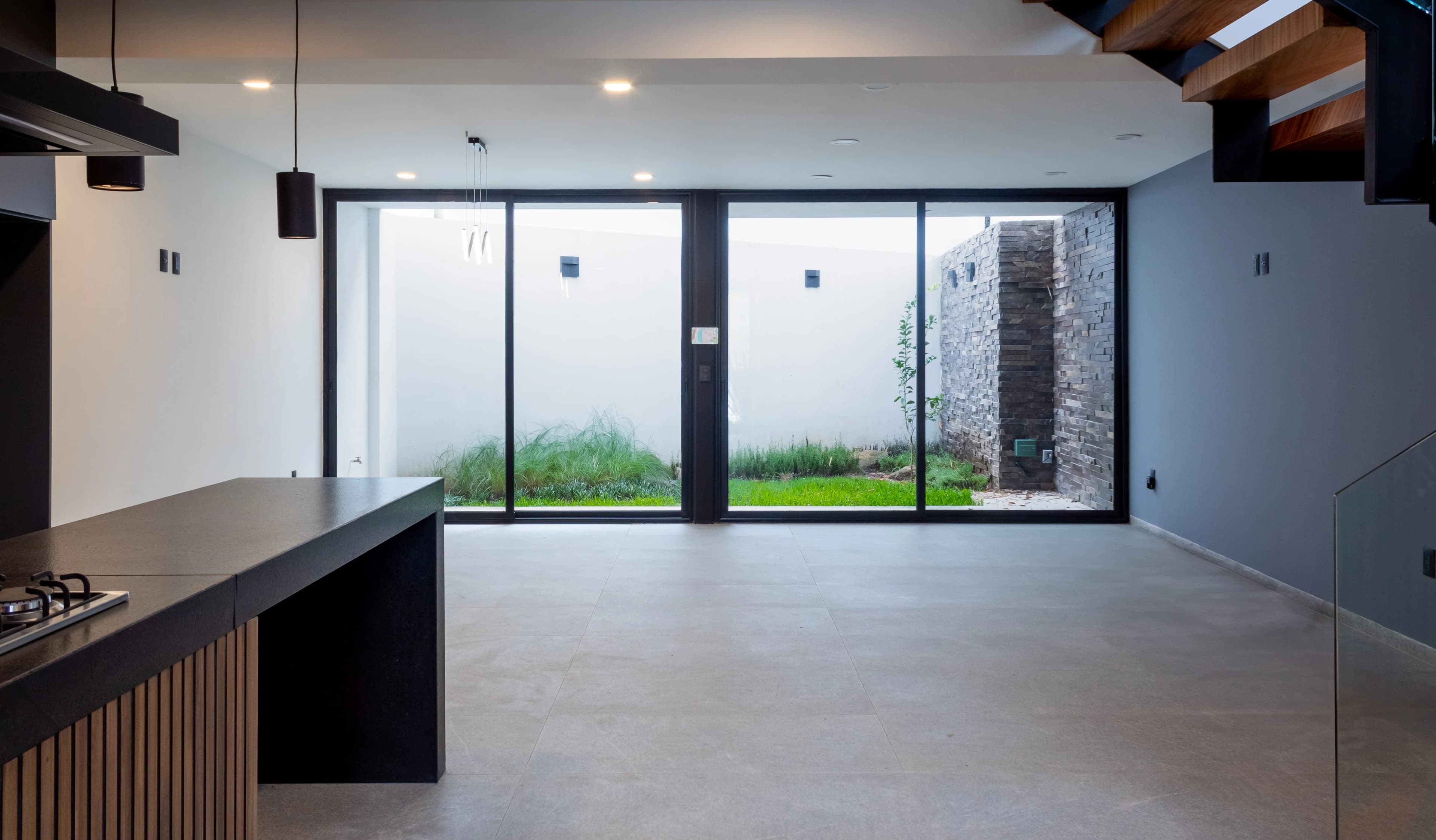 Estancia de Casa Encinos abierta al patio por un ventanal de piso a techo