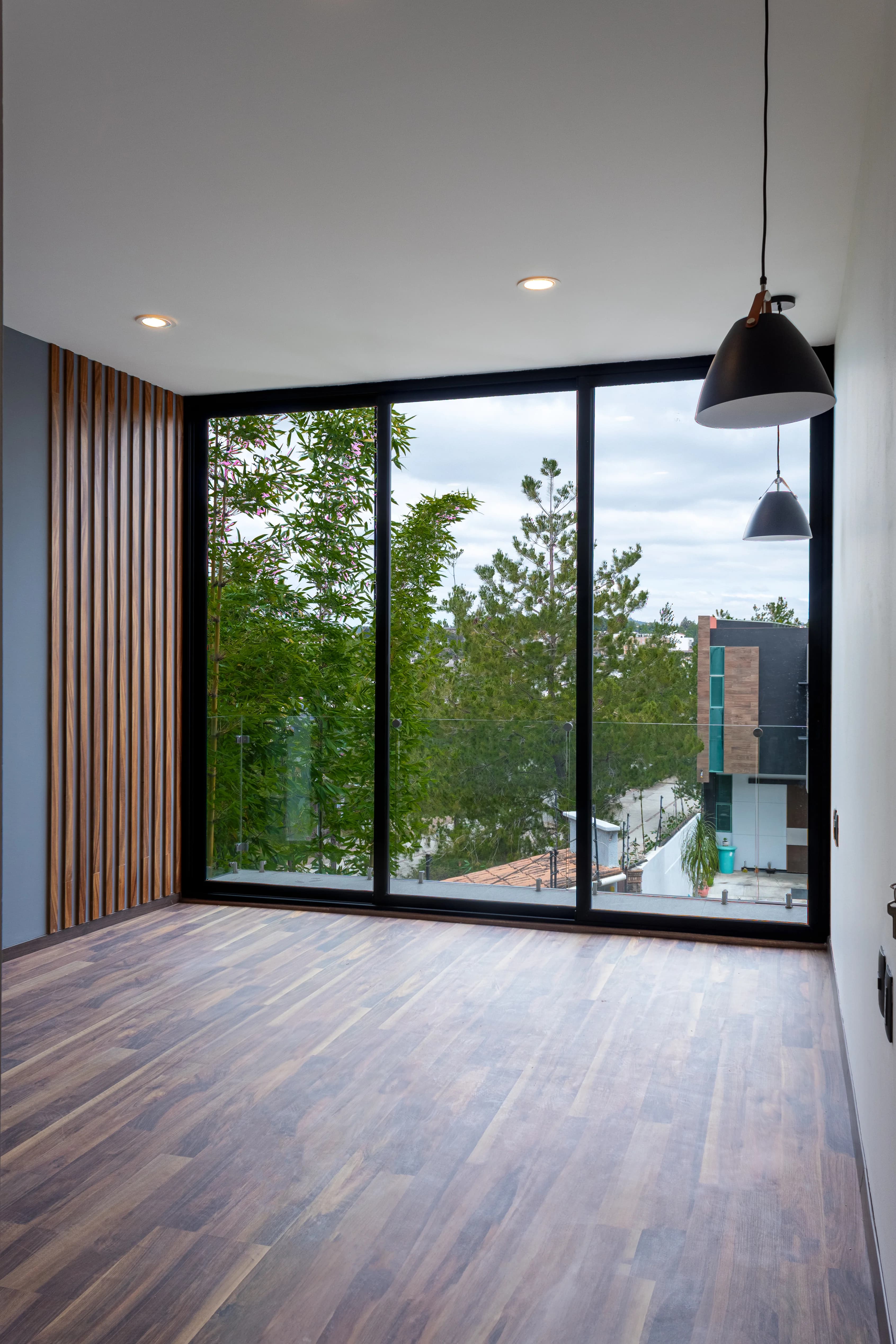 Sala de Casa Encinos en madera, con ventanal corredizo al jardín